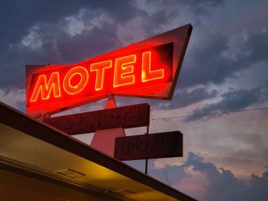 Koyu bulutlu arka planda kırmızı neon motelin düşük açılı görüntüsü.