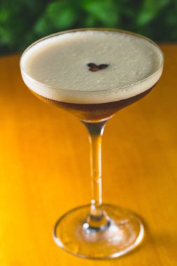 Ahşap masada cam bir bardak espresso martini kokteyli.
