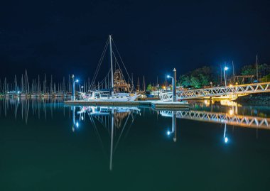 Tropikal Marina 'nın gece manzarası tekne ve liman ışıklarını yansıtıyor.