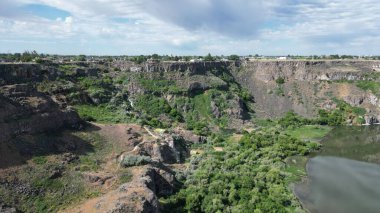 Bulutlu bir günde ağaçlı ve göllü güzel bir kanyon manzarası.