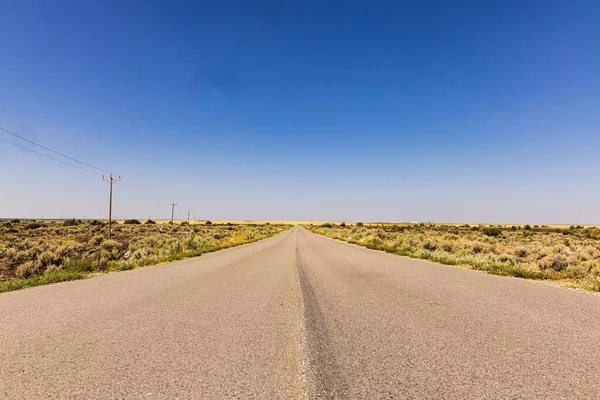 Eine Leere Straße Die Durch Trockene Felder Vor Blauem Himmel — Stockfoto