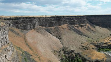 Kenardan bir kanyon manzarası ve arka planda mavi bir gökyüzü