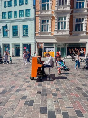 Almanya 'da Rostock caddesinde piyano çalan bir adamın dikey çekimi.