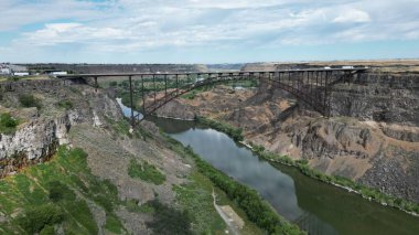 Kanyonları mavi gökyüzüne bağlayan nehir boyunca bir köprü.