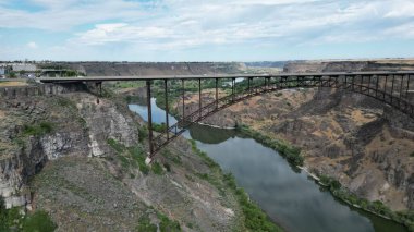 Gündüz vakti kanyonlar arasında nehrin üzerindeki bir köprü manzarası.