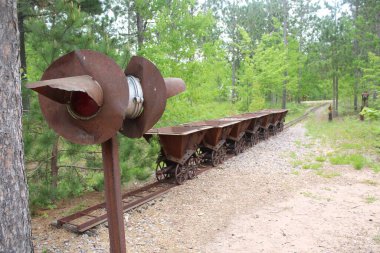 Eski metal cevherleri, yemyeşil bitkilerle çevrili terk edilmiş bir madende taşınıyor.