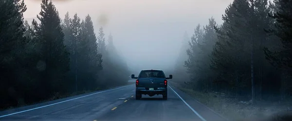 米国リグビー州イエローストーン国立公園の霧に覆われた道路に乗る車のバックビュー — ストック写真