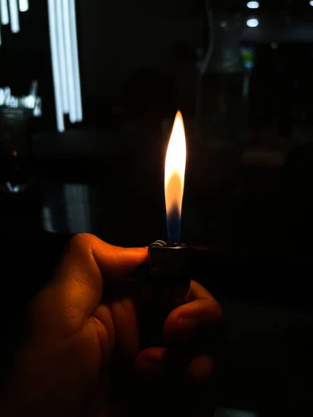 暗い背景のライターを点火する人間の手 — ストック写真