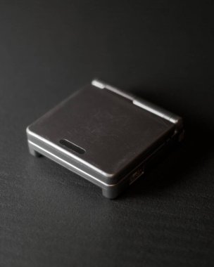 Siyah bir Gameboy, siyah arkaplan ile izole bir şekilde masada ilerliyor.