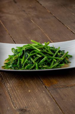 Tahta bir masada servis edilen ıspanağın dikey yakın çekimi.