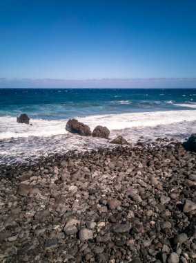 Tenerife 'deki mavi deniz dalgalarına karşı La Viuda plajının dikey görüntüsü.
