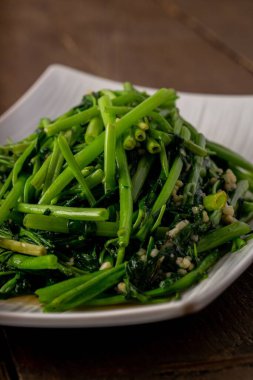 Tahta bir masada servis edilen ıspanağın dikey yakın çekimi.