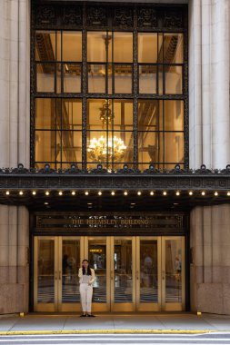 A vertical shot of the woman standing at the entrance of the Helmsley Building in Midtown Manhattan. clipart