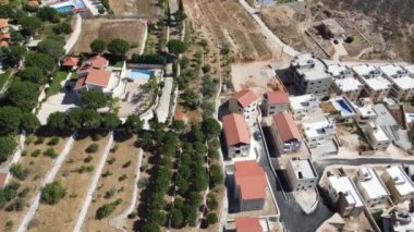 Güneşli bir günde yeşil ağaçlarla kaplı tepelerdeki villaların kuş bakışı görüntüsü.