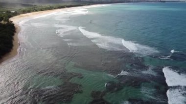 Güneşli bir günde köpüklü dalgalarla ve bir adayla güzel bir deniz manzarası