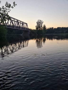 Güzel gün batımında nehrin üzerindeki bir köprünün dikey görüntüsü.