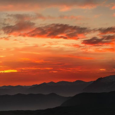 Gün batımında bulutlu gökyüzünün altında güzel bir dağ manzarası