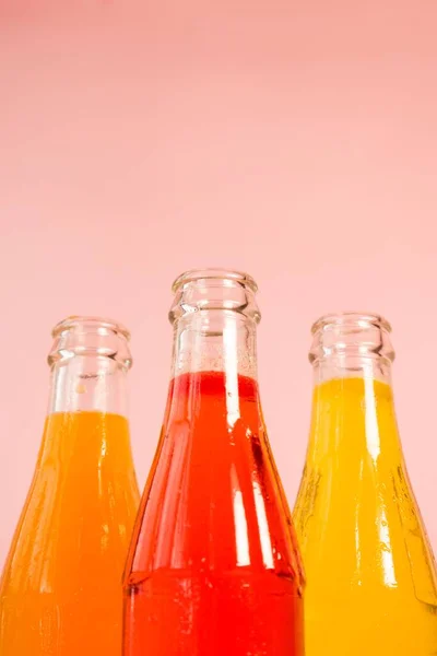 A closeup of juice bottles against the pink background