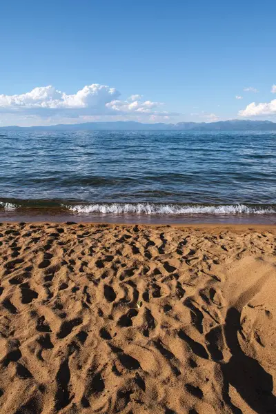 晴れた日の青い海の波に対する砂浜の垂直ショット — ストック写真