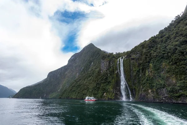 ニュージーランドの南島のミルフォードサウンドの滝の近くの小さな船 — ストック写真
