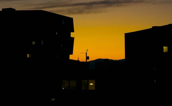 黄色の夕日の空に対するアパートの建物のシルエット — ストック写真