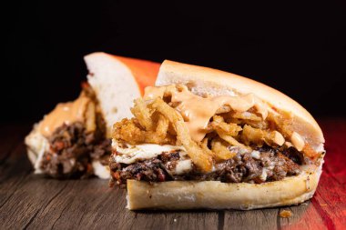 Ahşap yüzeyinde et, sos ve patates kızartması olan lezzetli sandviçlerin yakın plan çekimi.