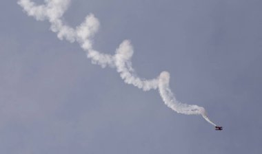 Gökyüzünde tirbuşon manevrası yapan çift kanatlı bir uçağın manzarası.