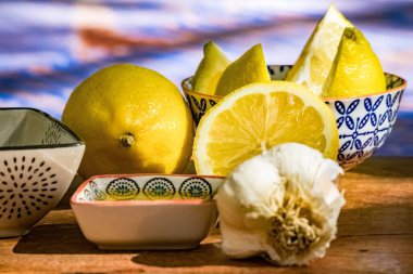 Kaplarda taze dilimlenmiş limon ve ahşap bir yüzey üzerinde sarımsak.