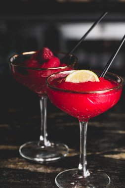 Barda bir bardak Cosmopolitan kokteyli ve ahududulu martini.