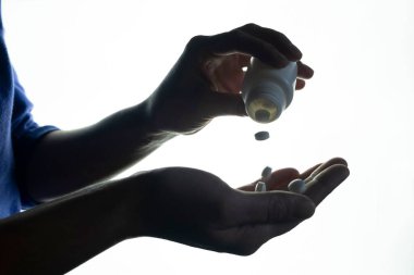 Konteynırdan avuç içine düşen hapların yakın çekimi.