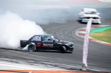 Siyah BMW E30 Valencia yarış pistinde patinaj yapıyor.