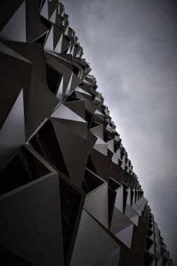 Gri gökyüzünün altındaki Parametrik mimari cephenin düşük açılı bir görüntüsü