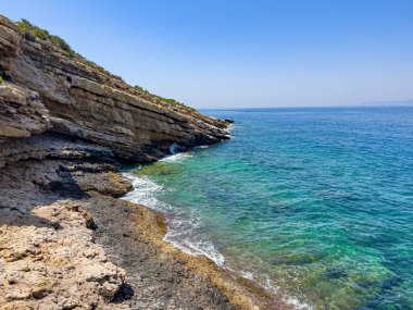 Mavi gökyüzüne karşı yeşil-mavi deniz ile kıyıdaki uçurumlar.