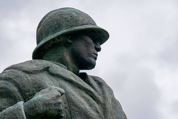 A closeup of soldier statue looking side in background of sky