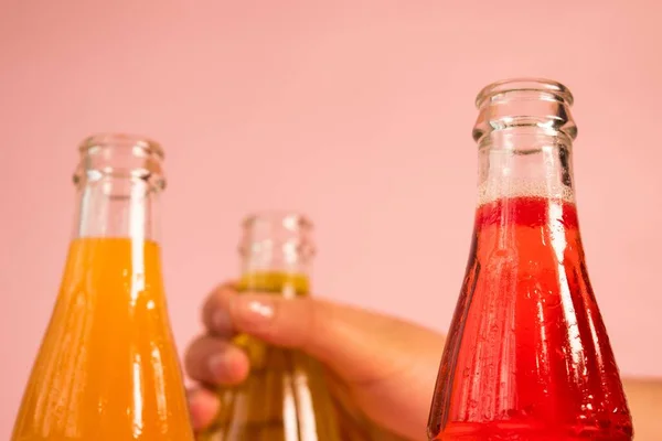 A closeup of juice bottles against the pink background