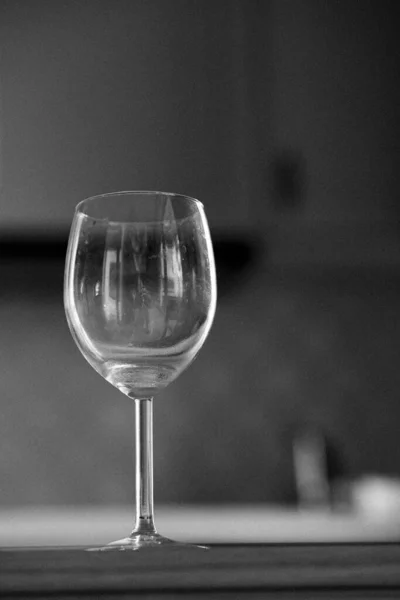 Вертикальный Черно Белый Снимок Стеклянной Чашки Столе Размытом Фоне — стоковое фото