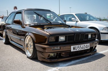 Kare farları ve açık bir kaputu olan güzel kahverengi BMW E30. dur- show