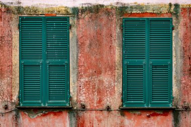Eski köy binasındaki yeşil pencerelerin yakın plan görüntüsü.
