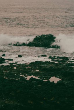 Çamur ve taşlarla körfeze vuran dalgaların dikey görüntüsü.