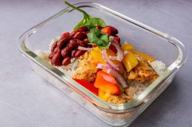 Cam bir kabın içinde tavuk ve fasulyeyle yakın plan bir pirinç tabağı.