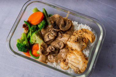 Dikdörtgen cam kasedeki tavuk eti, mantar, pirinç ve diğer sebzelere yakın çekim..