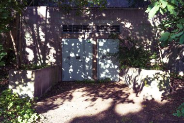 Güneşli bir günde, ağaçların gölgesi olan bir binanın kapalı kapısının güzel bir görüntüsü.