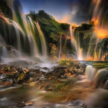Gün batımında bir ormanda güzel bir şelale ve dere manzarası.
