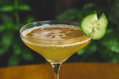 Bir parça salatalıkla servis edilen ferahlatıcı bir kokteylin yakından çekimi.