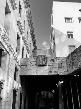 Kemerli girişi ve taş oyması olan bir binanın dikey gri tonlu görüntüsü.