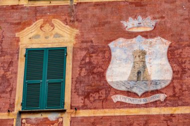 Neirone komünü sembolünün yakınındaki yeşil pencereli eski bina duvarının yakın çekimi.