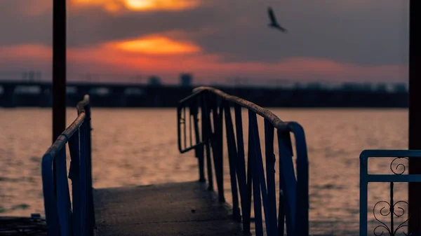 背景に夕日の海につながる古い金属製の桟橋 — ストック写真