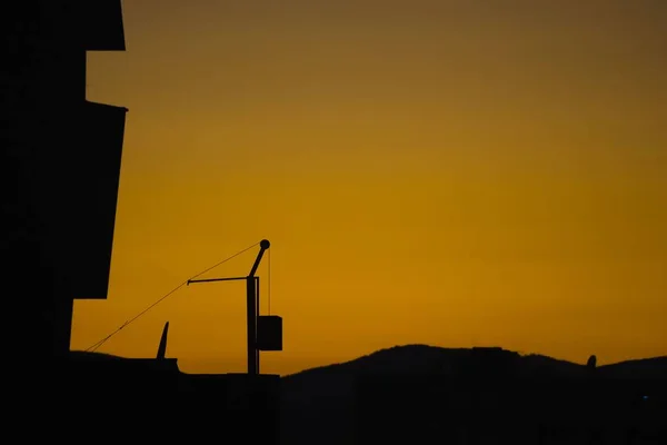 黄色落日的天空映衬下公寓楼和天线的轮廓 — 图库照片