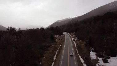 Yoldaki aracın dağlarla çevrili görüntüsü. Arjantin.
