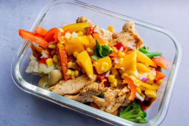 Şeffaf bir tabakta tavuk, patates ve çiğ sebze.